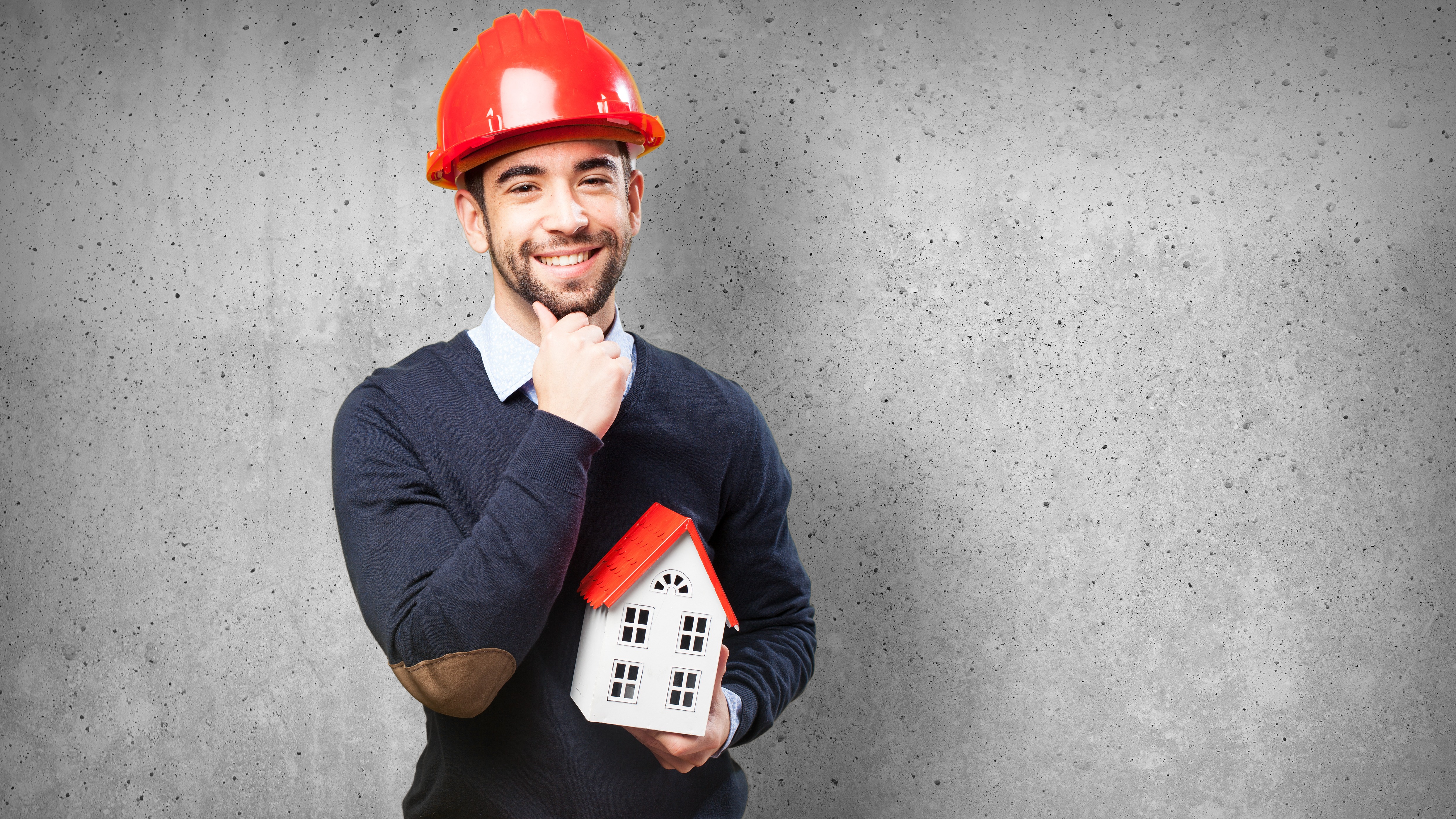 Architectural drawings and a hard hat on a desk overlooking a construction site.