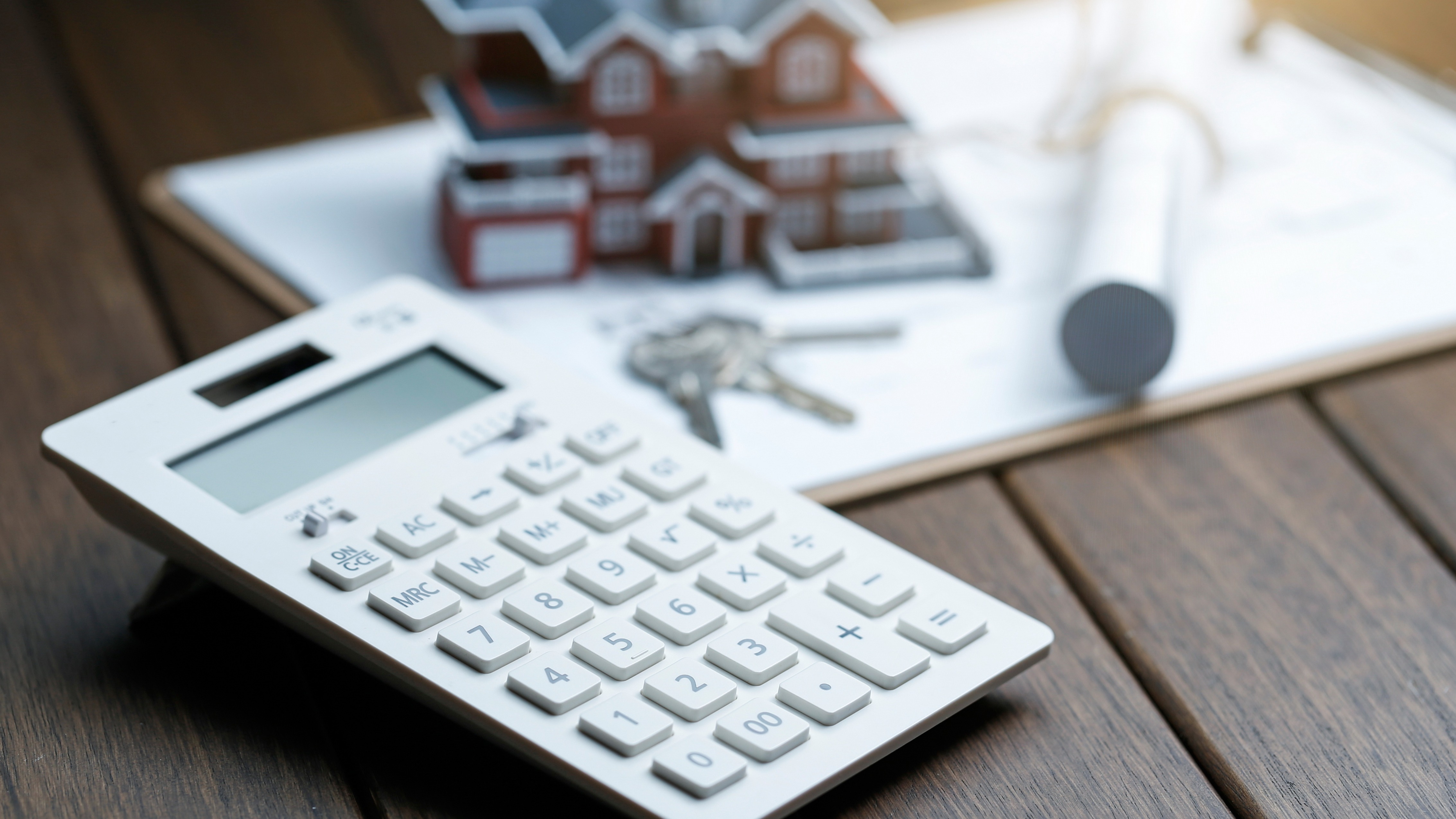 A person smiling while reviewing financial documents at a home desk, indicating a good deal.